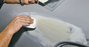 applying car body filler to rust damage